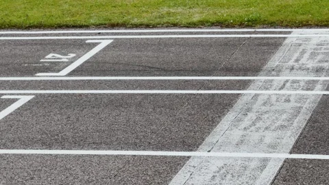 Close view of numbered asphalt lanes with crisp white markings beside green Stock Footage 345068102
