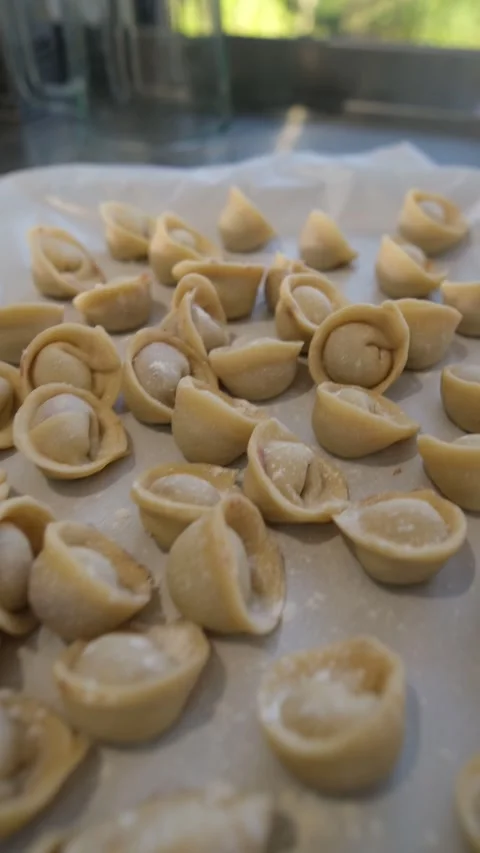 Close-up view of numerous raw, handmade pelmeni resting on parchment paper Stock Footage 318317564