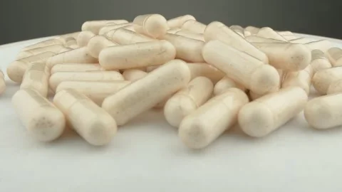A close up view of numerous white capsules scattered on a smooth surface 動画素材 341034213