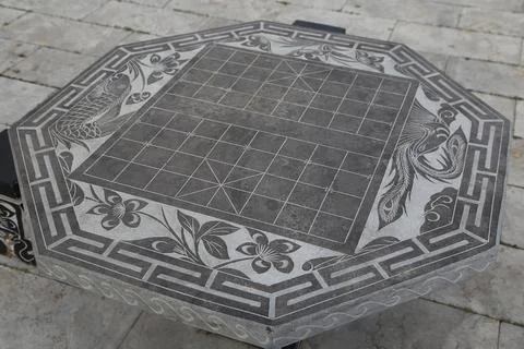 Close view of an octagonal stone game table engraved with floral and fish p.. Stock Photos