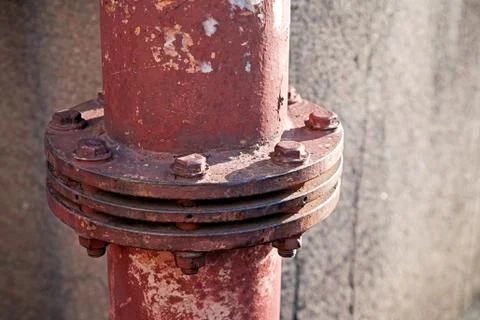 Close-up view of an old rough red painted tube connection with eight bolts on Stock Photos