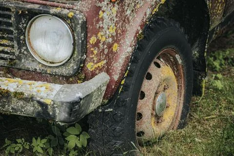 Close-up view of an old, rusty vehicle wheel with a flat tire, covered in m.. Fotos de archivo