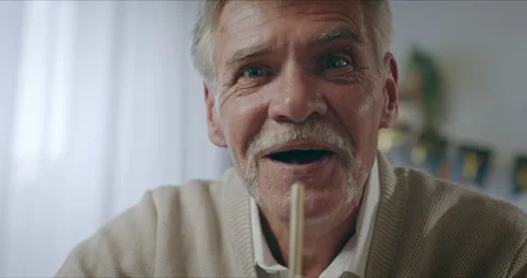Close-up view of old senior man's face blowing up burning candle in front of web Stock-Footage 139529520