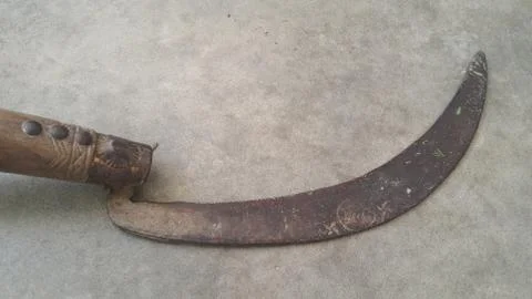 Close-up view of an old sickle (reaping-hook) on the concrete surface Foto stock