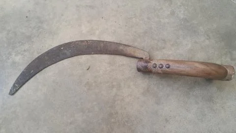 Close-up view of an old sickle (reaping-hook) on the concrete surface Foto stock