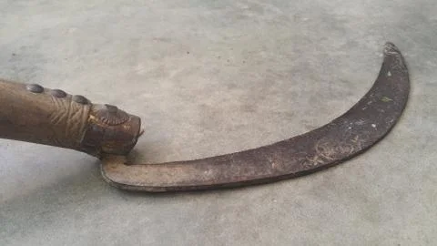 Close-up view of an old sickle (reaping-hook) on the concrete surface Stock Photos