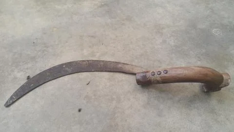 Close-up view of an old sickle (reaping-hook) on the concrete surface Stock Photos