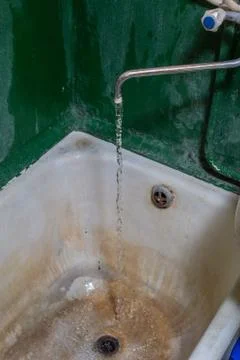 Close view of old stained water tap and rusted bathtub with selective focus and Фото