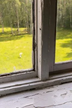 A close-up view of an old window reveals extensive peeling paint and grime. O Stock Photos