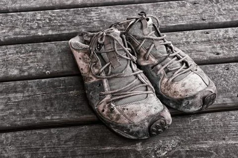 Close view on an old worn boots standing on a wooden floor Stock Photos