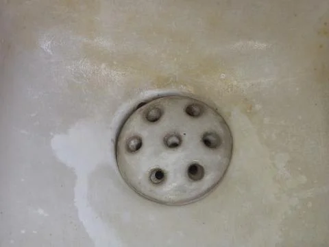 Close-up View of an Old, Worn, Off-white Sink Basin with a Circular Drain Foto stock