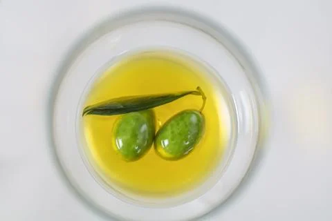 Close up view of olives and extra virgin olive oil with olive leaf on white b Stock Photos