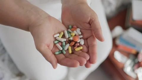 Close up view of open hands holding a large pile of colorful medical pills. 스톡 동영상 336662689