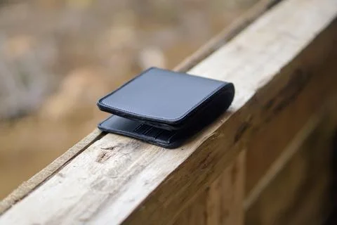 Close-up view of an open modern black leather wallet on a wooden outdoor surface Stock Photos
