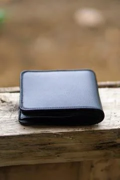 Close-up view of an open modern black leather wallet on a wooden outdoor surface Stock Photos