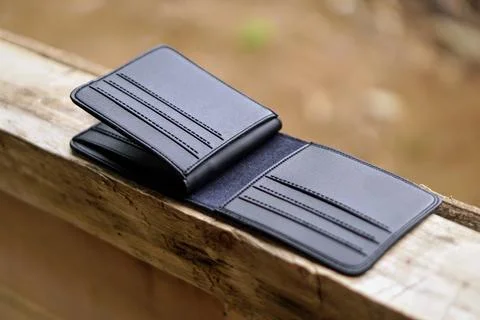 Close-up view of an open modern black leather wallet on a wooden outdoor surface Stock Photos