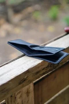 Close-up view of an open modern black leather wallet on a wooden outdoor surface Stock Photos