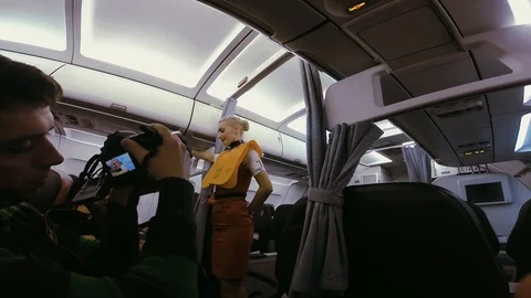 Close up view of an operator with camera filming the young stewardess who 스톡 동영상 105276625