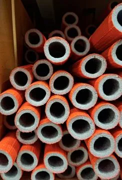 Close up view of orange foam pipe insulation tubes stacked together in a co.. Photos