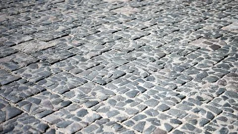 Close up view of an outdoor paved surface featuring dark grey irregular cobbl Stock Photos