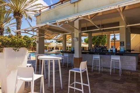Close-up view of outdoor poolside bar with white chairs and tables on background Stock Photos