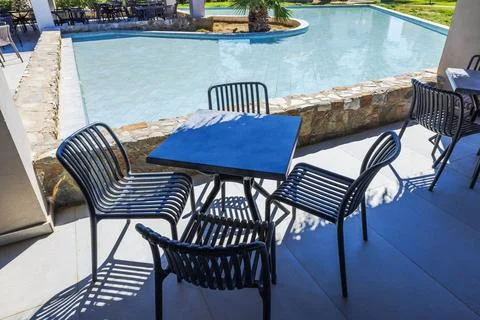 Close up view of outdoor terrace with table and chairs near hotel swimming pool Stock Photos