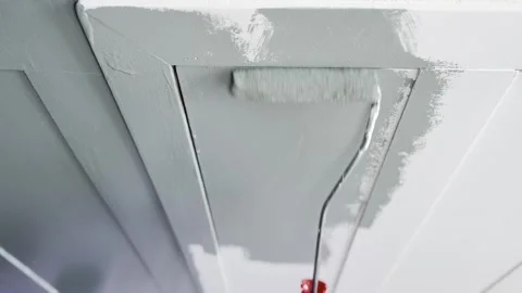 A close-up view of a paint roller applying a coat of gray paint to a smooth Stock Footage 332626578