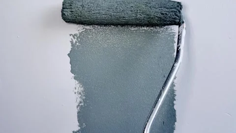 A close-up view of a paint roller applying a coat of gray paint to a smooth Stock-Footage 332626622