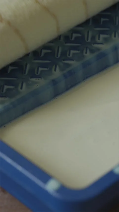 Close up view of paint roller squeezing excess primer in tray Stock Footage 340404931
