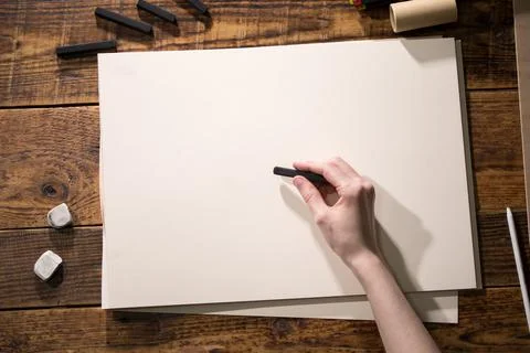 Close-up view of a painter on a white sheet. A man holds a pencil and draws.  Stock Photos