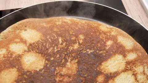 A close-up view of a pancake being cooked in a frying pan. Stock Footage 255252309