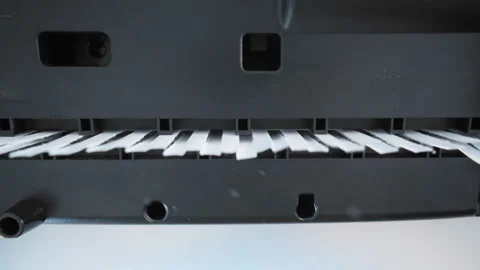 A close up view of a paper shredder cutting a sheet of office paper into thin Stock Footage 297086740
