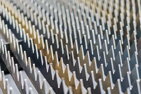 Close-up view of a parallel, uniform row of metallic spikes on a steel-like.. Stock Photos
