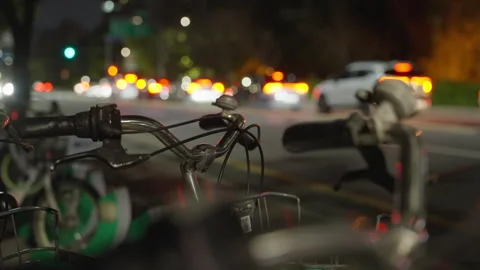 Close-up View of Parked Bicycles with Bokeh City Traffic Lights and Cars on a Video stock 310348919