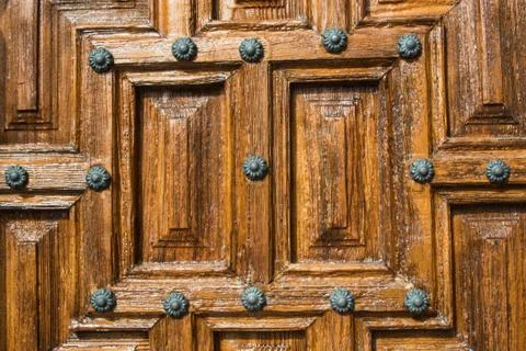 A close-up view to a part of old brown wooden door with metal rivets. Stock Photos