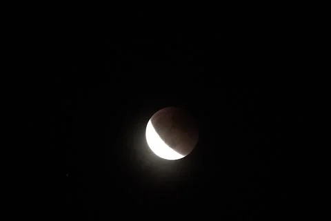 A close-up view of a partial lunar eclipse against the dark night sky. Stock Photos