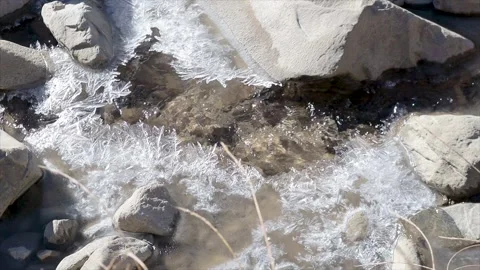 Close-up view of a partially frozen mountain stream with intricate ice crys.. Video stock 311887446