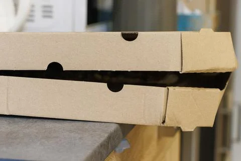 A close-up view of a partially opened cardboard pizza box resting on a Stock Photos