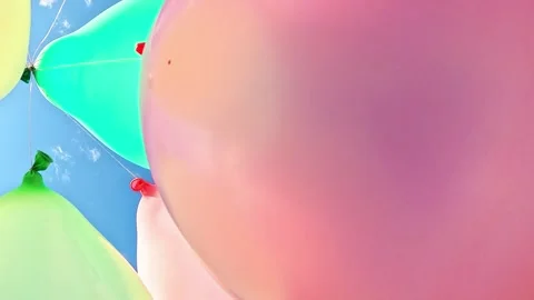 Close view of pastel balloons drifting across tranquil blue sky Stock Footage 317591820