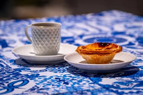 Close view of pastel de nata custard tart with coffee cup on blue tablecloth on 스톡 사진