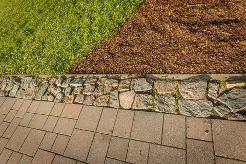 Close-up view of a path with interlocking bricks, a central stone border. Stock Photos