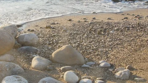 A close-up view of a pebbled beach during the golden hour, featuring gentle Stockbeeldmateriaal 333469356