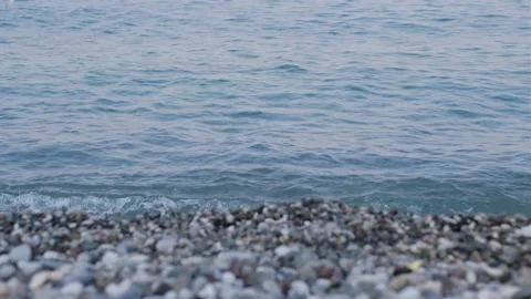 Close-up view of pebbles on a beach with gentle waves lapping at the shore 動画素材 346723969