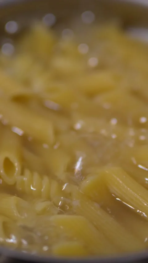 A close-up view of penne pasta boiling in a pot. Stock Footage 328844791