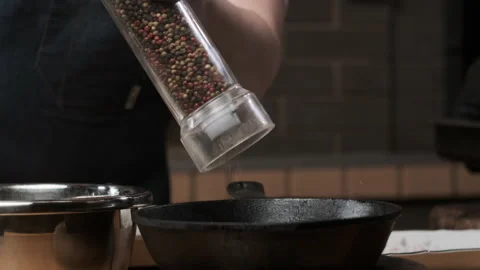 Close up view of pepper grinding peppers directly into black cast iron pan Stock Footage 151051136
