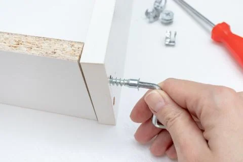 Close up view of a person assembling new white drawer using a screwdriver, ti Stock Photos