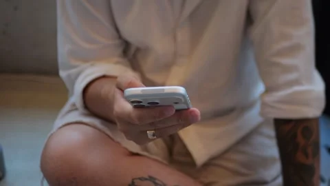 Close-Up View of Person Browsing on Smartphone While Sitting Indoors... 動画素材 334437217