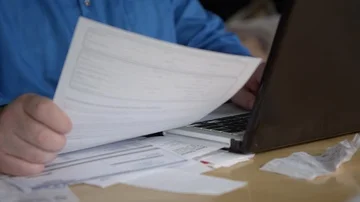 Close view of person looking at bills then typing on laptop Video stock 85593462
