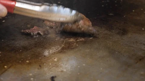 Close view person prepares meat on frying surface with tongs Stock Footage 104841469