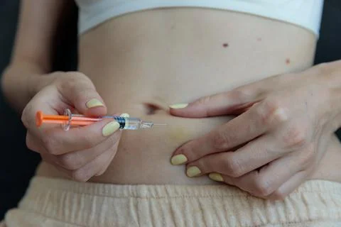 A Close-Up View of a Person Preparing to Inject Medication into Their Abdomen Stock Photos